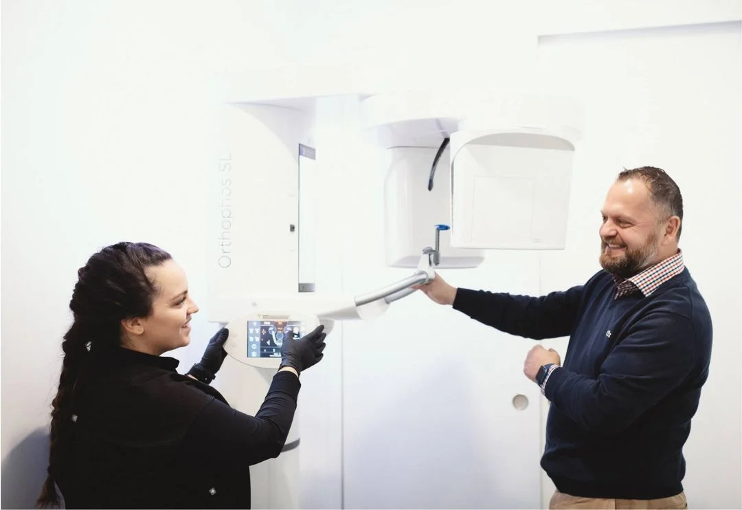 Dentist and patient smiling during a digital X-ray at Dimension Dental office